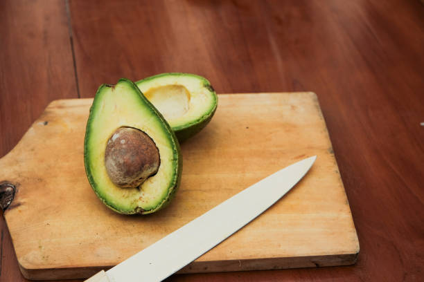 istock Halved avocado with pit and kitchen knife on wooden cutting board 2200043646