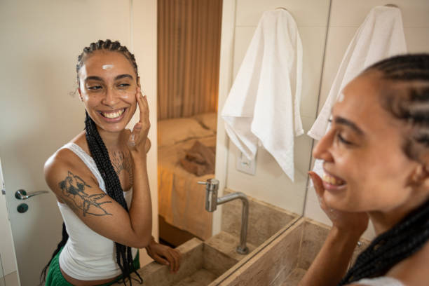 istock Woman smiling at the mirror while applying cream and doing her morning skincare routine 2200043893