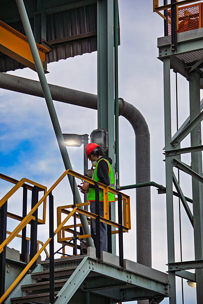 istock man contractor worker climbed industrial metallic structure with safety gear and hardhat using the phone, wearing workwear 2200045285