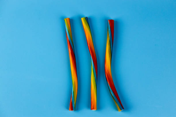 Three colorful twisted candy straws displayed on a light blue background, showcasing a delightful mix of vibrant hues. Ideal for festive occasions or as a sweet treat.