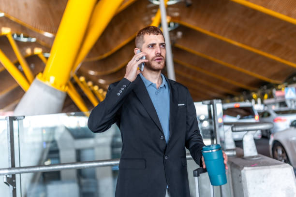 istock Businessman talking on phone while holding reusable coffee cup at airport 2200048466