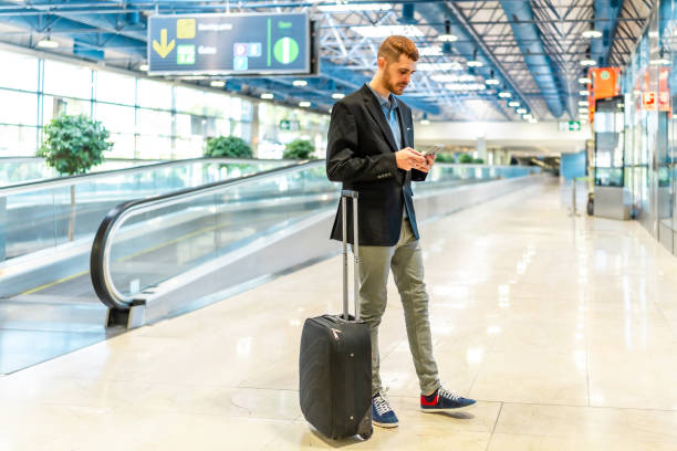 istock Businessman using smartphone while walking through airport terminal 2200048663