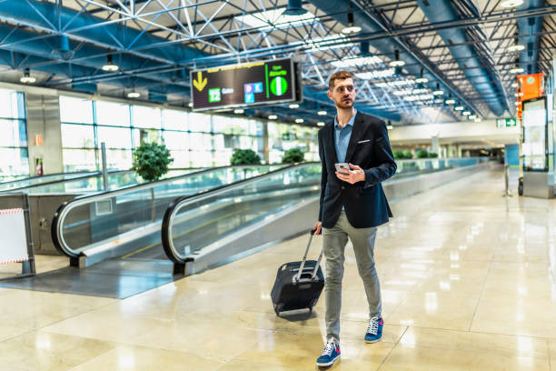 istock Businessman walking through airport terminal while using smartphone 2200048670