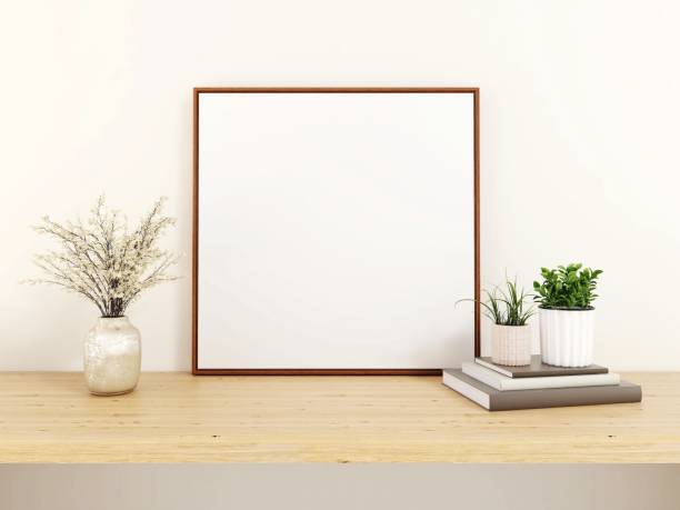istock Blank square frame mockup, ornaments, plants and books on a table 2200051060
