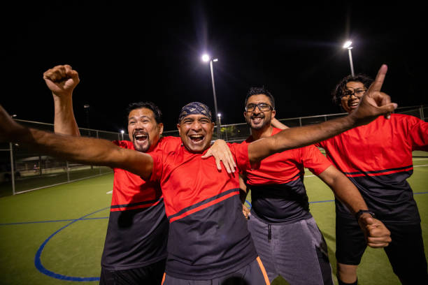 Group of diverse soccer athletes celebrating a hard-earned goal on the field, with smiles, hugs, and high-energy excitement shared among teammates.