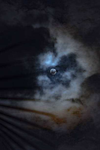istock Full moon hidden in the clouds at night. Partial eclips. A luminous full moon obscured partially by fast-moving clouds 2200055940