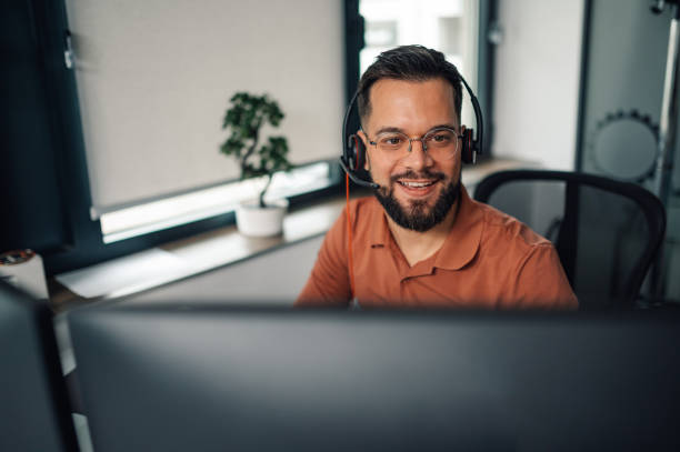 istock Smiling male call center agent working on computer in office 2200058549