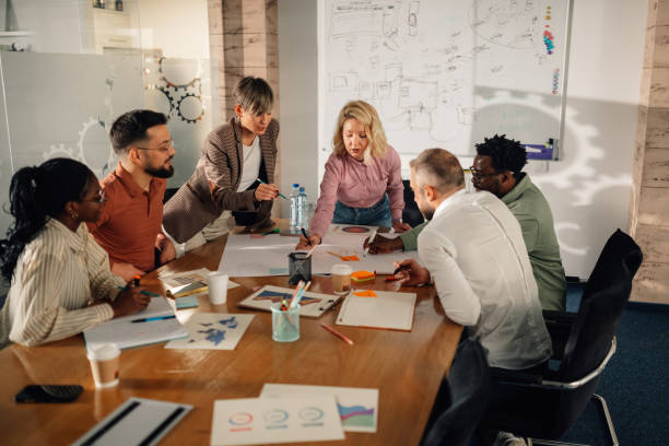 Marketing professionals collaborating on project in modern office Diverse team of marketing professionals working together on a project in a modern office, analyzing charts and graphs on a large table marketing stock pictures, royalty-free photos & images