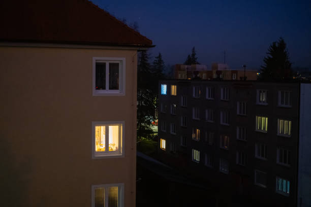 istock Warm apartment window lights in dark residential area 2200060886