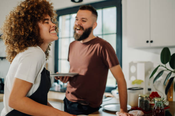 istock Happy couple washing dishes and having fun in kitchen 2200061762