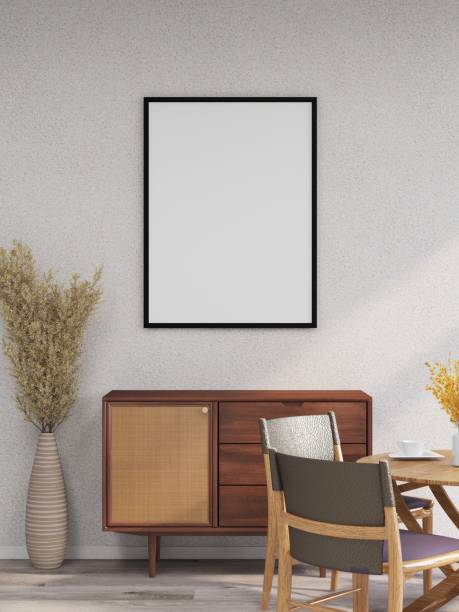 istock Mockup of vertical frame on a white wall, sideboard, table with chairs and ornamental plants 2200062895