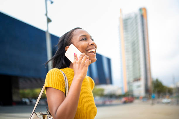 istock Cheerful black lady talking on mobile phone outdoors in city 2200065336