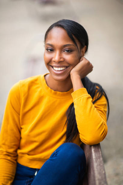 istock Happy black woman sitting outdoors on bench 2200065557