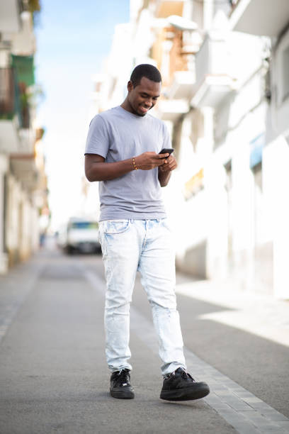 istock Happy young african man texting on mobile phone walking outside 2200065652