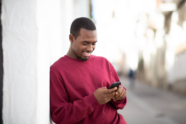 istock Handsome young african man texting on mobile phone outside 2200065750