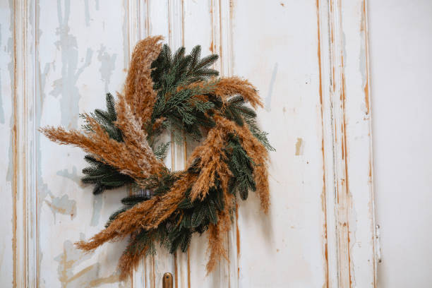 istock Elegant dried grass and evergreen wreath on rustic white door 2200065909