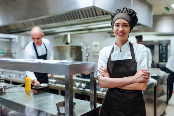 istock Confident female chef smiling with arms crossed in a restaurant kitchen 2200065949
