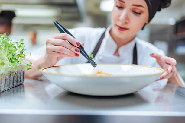 istock Chef carefully placing microgreens on dish with tweezers in restaurant kitchen 2200065987