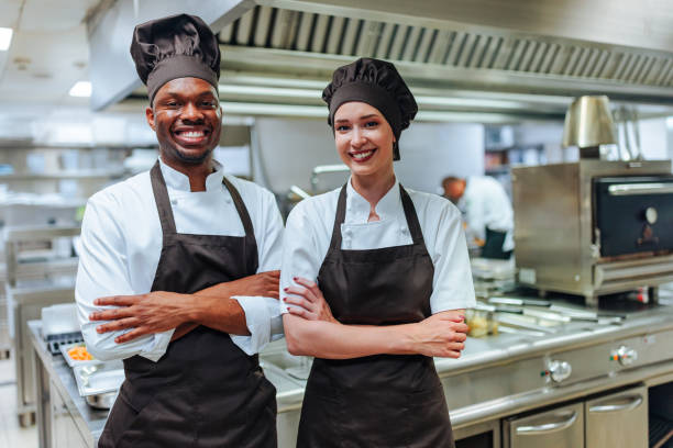 istock Two smiling chefs posing with arms crossed in a restaurant kitchen 2200066005