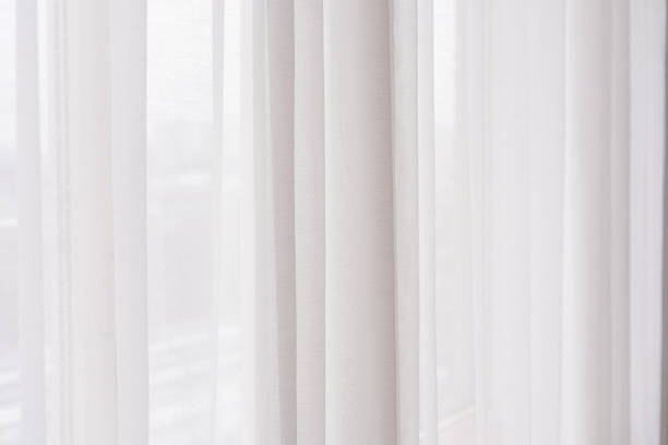 istock Soft white curtains gently filtering light in bright indoor space 2200066063