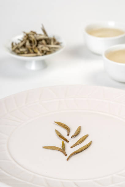 Tea leaves and tea in white cup on white background