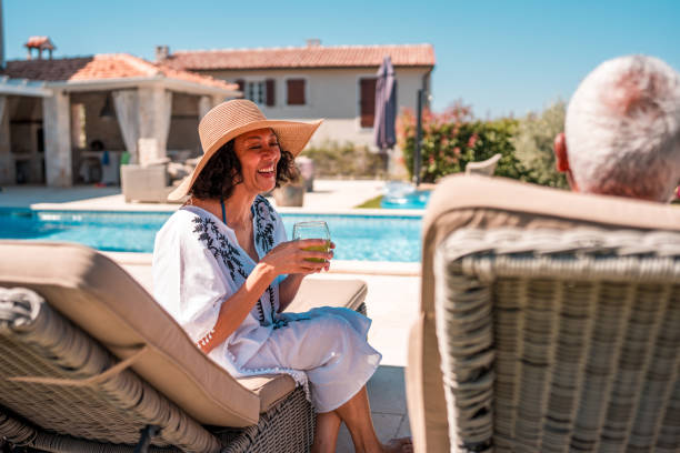 istock Senior Couple Enjoying Refreshing Drinks in Deckchairs by the Pool 2200082277