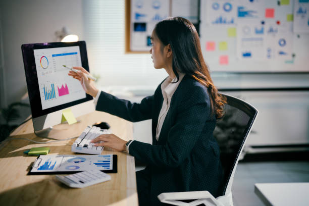 istock Young businesswoman is pointing at computer screen showing charts and graphs, analyzing financial data while working on a project in a modern office 2200084568