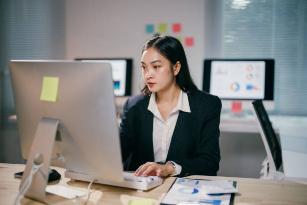 istock Focused businesswoman concentrating on her work on computer, typing on keyboard and analyzing data on desktop screen in a modern office at night 2200084758