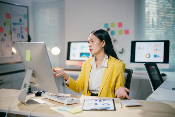 istock Frustrated Asian businesswoman working at desktop computer, displaying stress through hand gestures and intense screen stare in contemporary workspace 2200084825