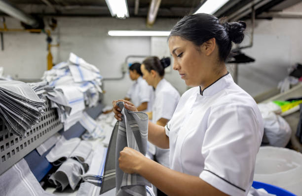 istock Employee working at an industrial dry cleaner folding napkins 2200085552