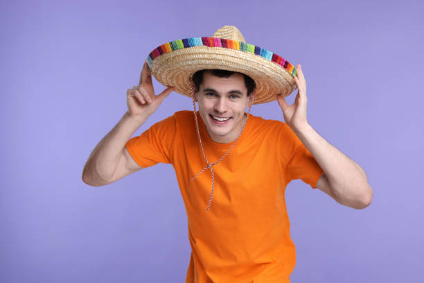 Young man in Mexican sombrero hat on violet background