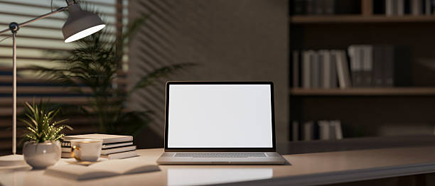 istock A close-up of a laptop sit on a table in a modern office, softly illuminated by a table lamp. 2200087913