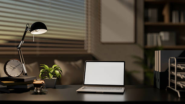 istock A modern office features a laptop with a white screen mockup and decorative items on a black desk. 2200087933