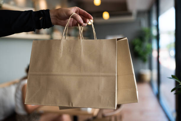 istock Elegant hand holding a stylish brown paper bag. 2200089864