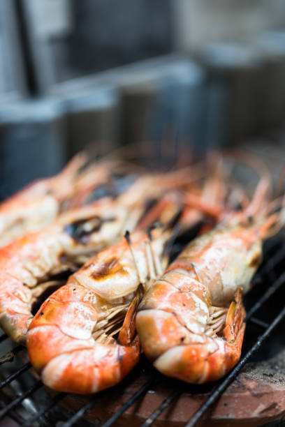 Grilled giant river prawns over charcoal fire.