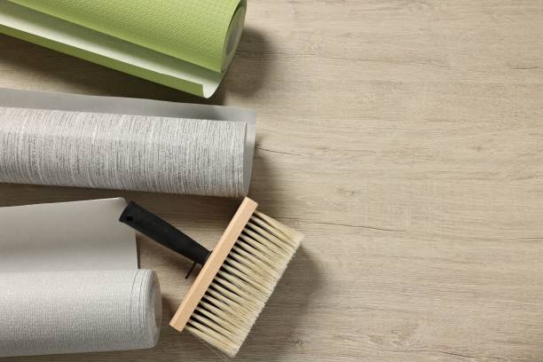 istock Different wallpaper rolls and brush on wooden table, flat lay. Space for text 2200092551