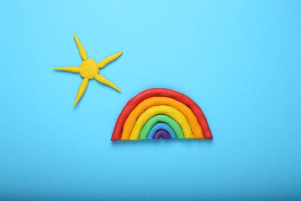 istock Rainbow and sun made of plasticine on light blue background, top view 2200092589