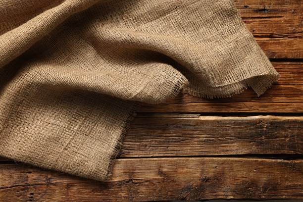 istock Burlap fabric on wooden table, top view 2200092601