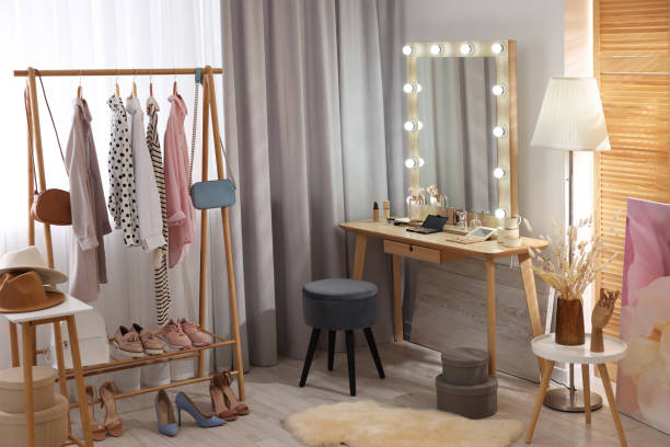 istock Makeup room. Stylish dressing table with mirror, chair and clothes rack indoors 2200093247