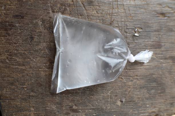 istock Transparent plastic bag filled with water resting on rustic wooden surface 2200099317