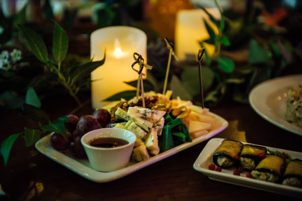 istock Assorted cheeses on a white plate with honey, walnuts and red grapes. A plate with a variety of cheeses on the table in the restaurant, decorated with green stems and leaves 2200099378