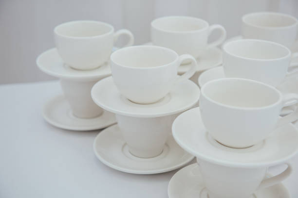 istock Lots of empty tea or coffee cups on a white table against a white wall, space for text.  Organization of events, catering, catering, beautiful white and gray background 2200100846