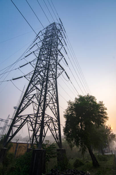 High voltage electricity transmission tower, also known as an electricity pylon, standing tall against a clear sky, representing power infrastructure and energy distribution.