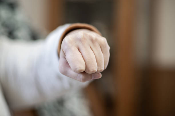 An isolated arm with a clenched fist on a clean white backdrop, emphasizing strength