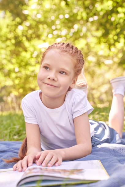 istock Joyful child relaxing outdoors with a book in sunny park setting 2200108806