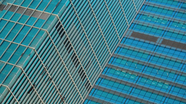 istock Two modern skyscrapers intersect at an angle, showcasing contrasting architectural styles. The repetitive grid patterns and blue-tinted glass create a dynamic urban aesthetic. 2200110616
