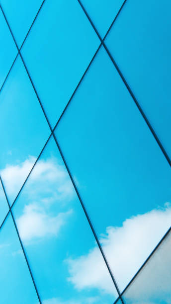 istock a close-up of reflective glass panels arranged in a diamond pattern, capturing the soft blue sky and fluffy white clouds. The interplay of geometry and reflection creates a serene and modern aesthetic. 2200110672