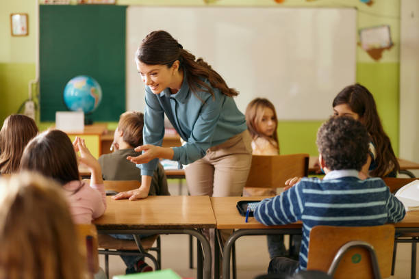 istock Happy teacher talking to her student on a class at elementary school. 2200112089
