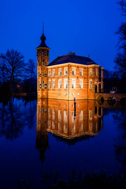 Breda, The Netherlands. February 14th, 2025: Castle Bouvigne in Breda, The Netherlands, beautifully illuminated during the blue hour. The historic castle, surrounded by water and lush gardens, reflects gracefully in the calm surface of the pond. The deep blue sky contrasts with the warm lighting of the building, creating a magical evening atmosphere. This serene scene showcases the charm and heritage of one of Breda’s most picturesque landmarks.