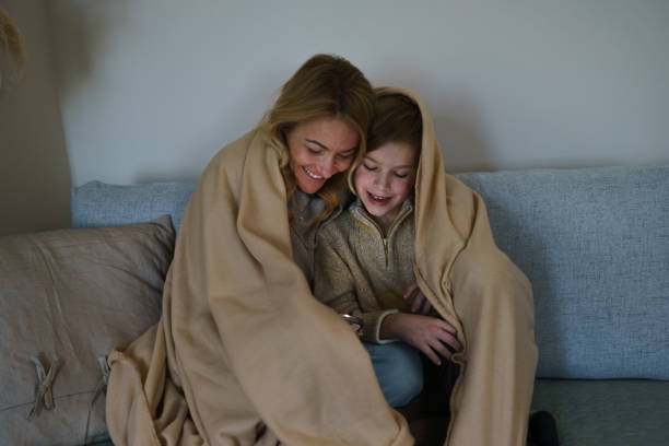 istock A mother and son are sitting on the sofa and using a mobile phone 2200116194